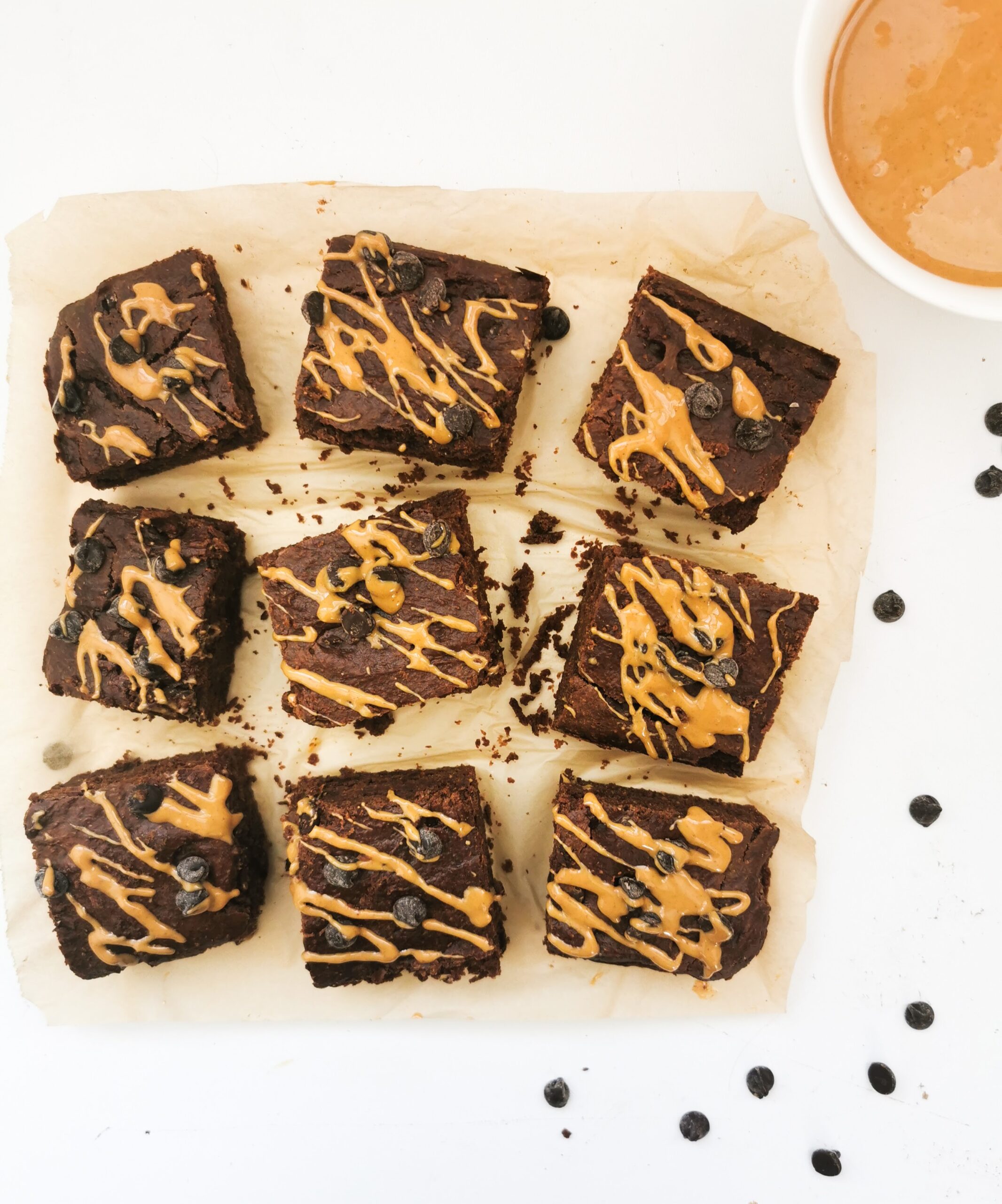 Brownies au chocolat avec un glaçage au beurre d'arachide, présentés sur du papier sulfurisé, avec des pépites de chocolat sur le dessus.